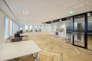 Modern open-plan office space on Hiridostraat with workstations, a glass meeting room, and a kitchenette.